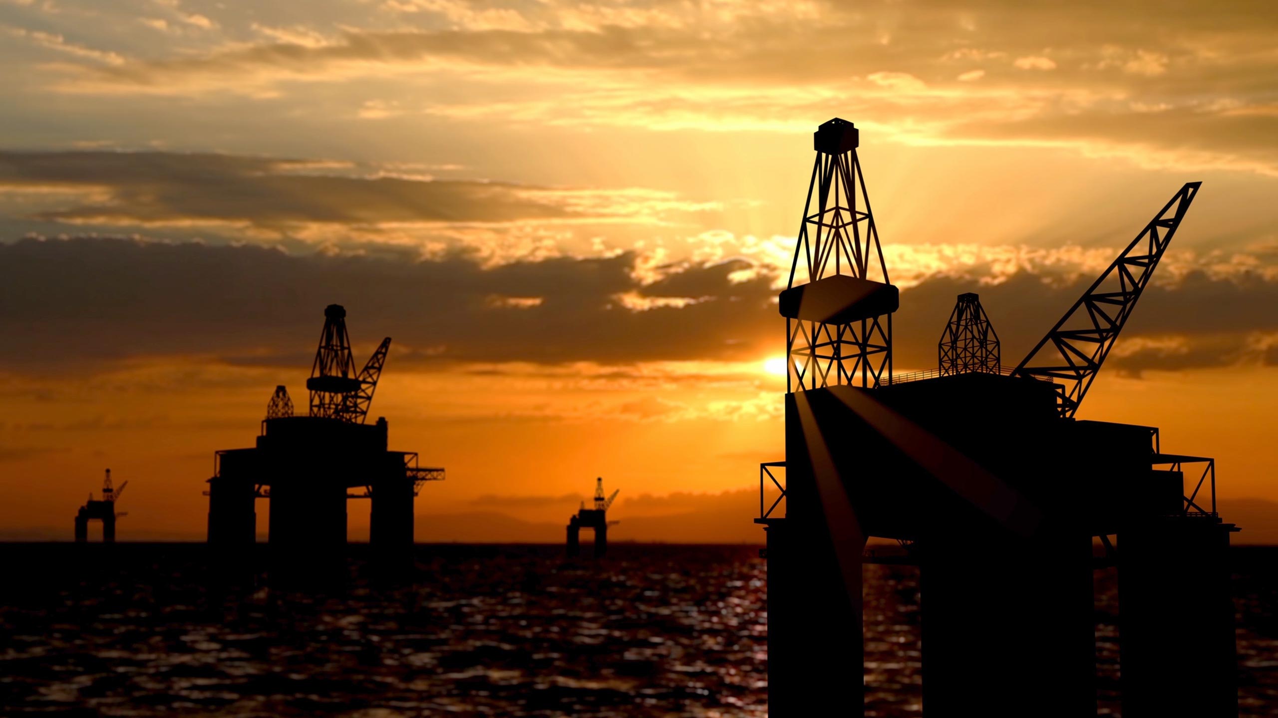 A sunset photo of sea-based oil rigs